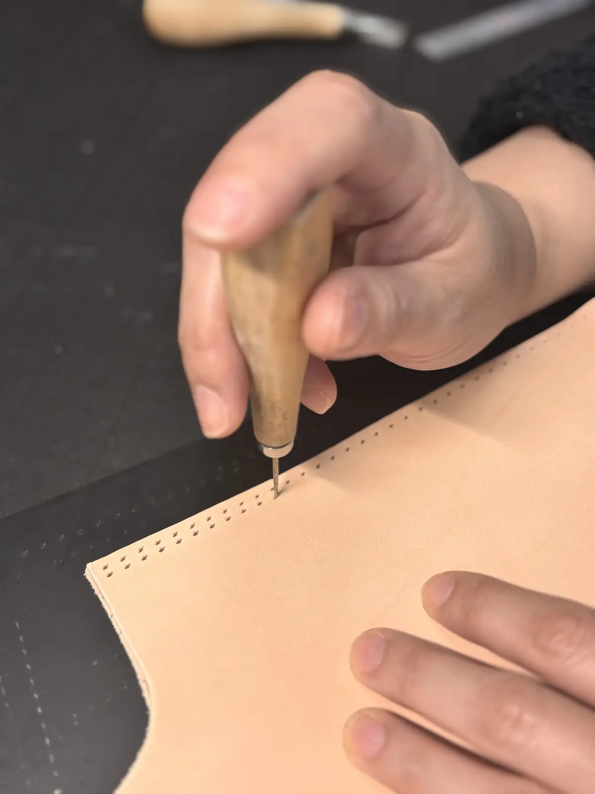 革に手作業で縫い穴を開けている様子